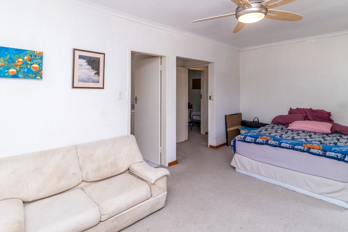 A functional bedroom featuring carpeted flooring, a ceiling fan, and direct access to adjacent rooms.
