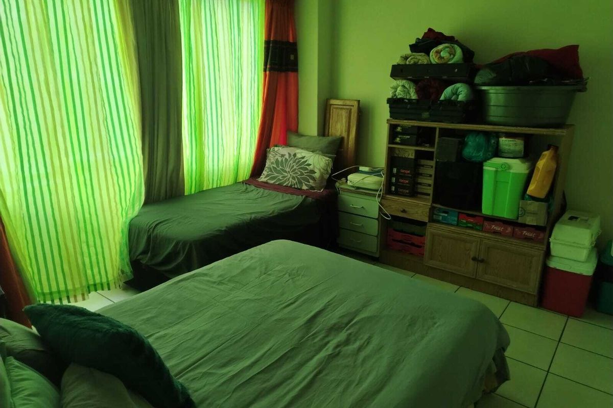 A bedroom featuring tiled flooring and large windows with curtains, providing natural light to the space.
