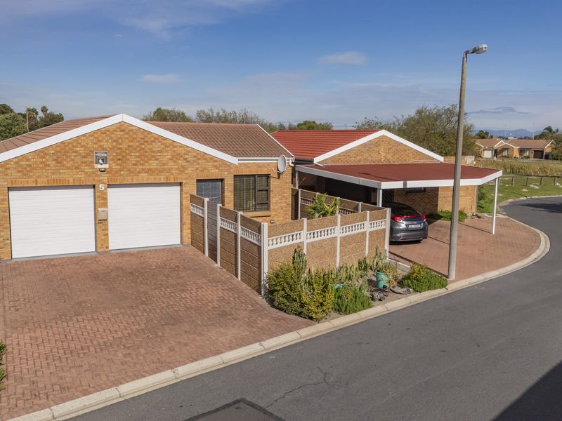Front elevation of a facebrick house featuring a double garage, attached carport, and paved driveway within a residential estate setting.