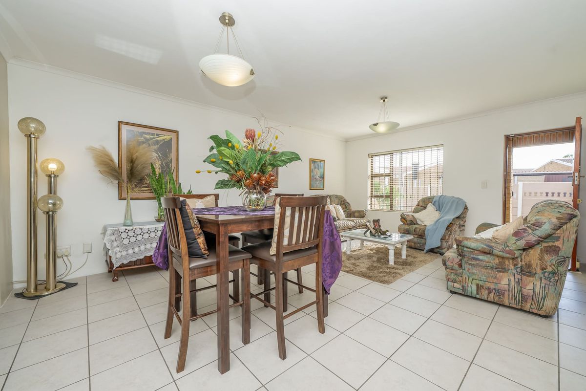 Spacious open-plan living and dining area featuring neutral tiled flooring, large windows with venetian blinds, and direct access to the exterior.
