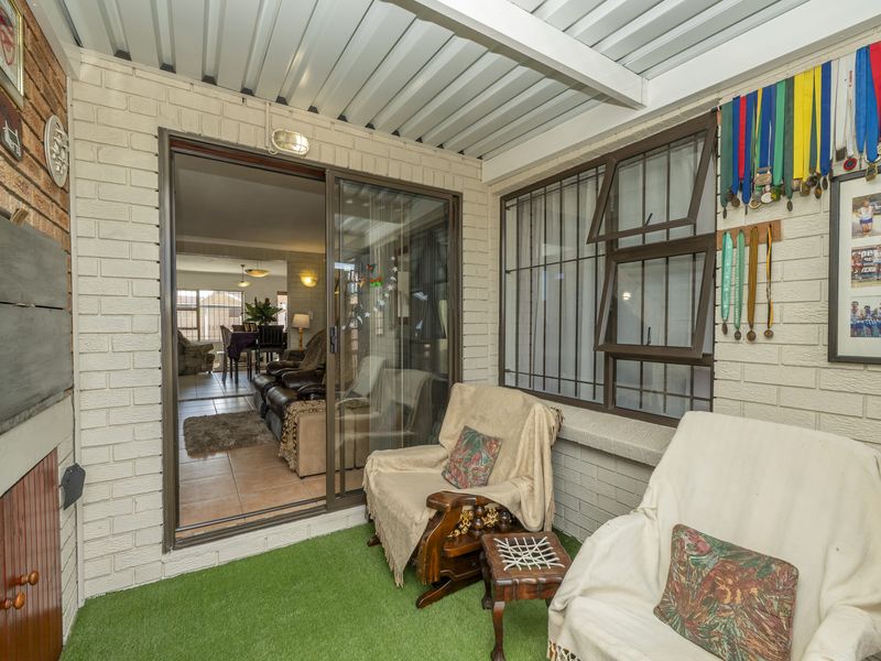 A covered patio area featuring a corrugated metal roof, brick walls, and a sliding glass door providing access to the interior living space.