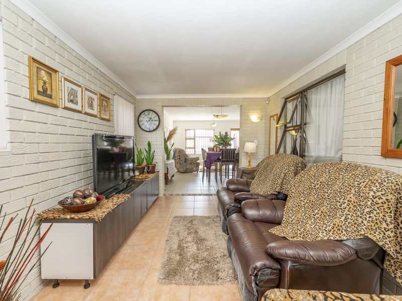 Open-plan living area featuring painted brick walls and ceramic floor tiles, providing a connected space between the lounge and dining area.