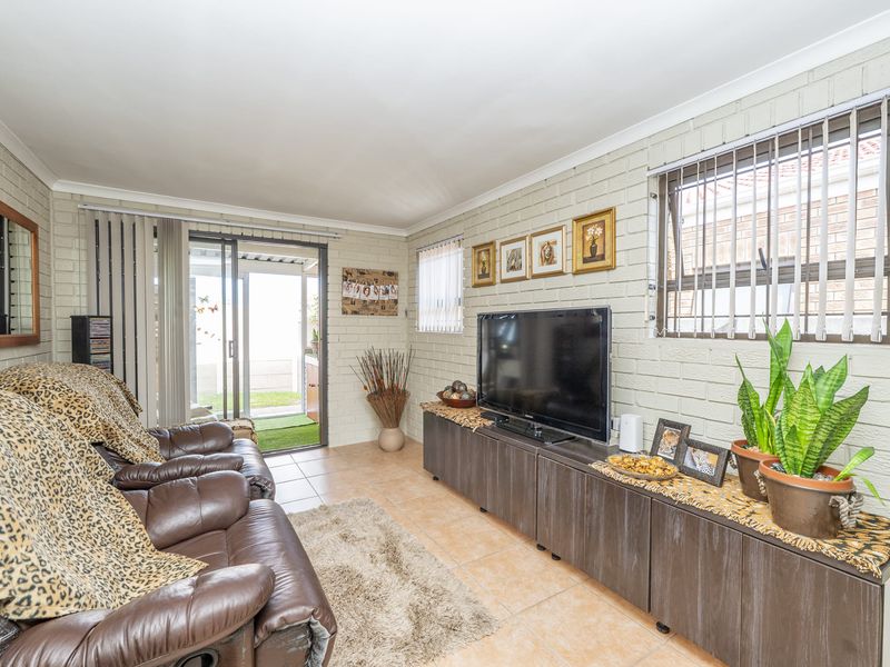 A living room featuring painted brick walls, ceramic tile flooring, and a sliding glass door providing access to the outdoor area.