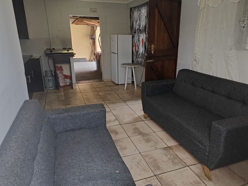 Open plan living area featuring tiled flooring and a compact kitchen corner with a gas stove.