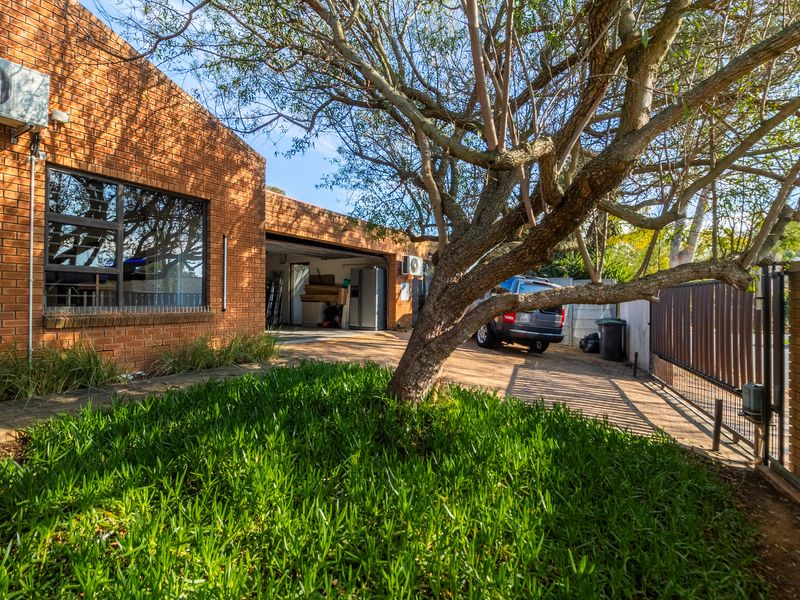 Front exterior view of the property featuring a brick facade, paved driveway, integrated garage, and established garden area.