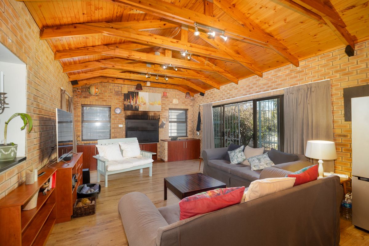 Spacious living room featuring exposed timber rafter ceilings, face brick walls, and large sliding glass doors leading to the exterior.