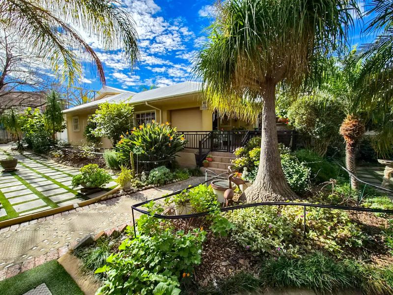 A well-maintained front exterior featuring a landscaped garden, paved walkway, and a covered porch entrance.