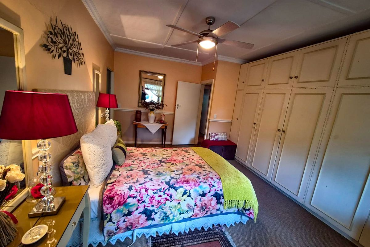 A spacious bedroom featuring extensive built-in wardrobes, a ceiling fan, and classic coving details, offering a functional layout with potential for modern updates.