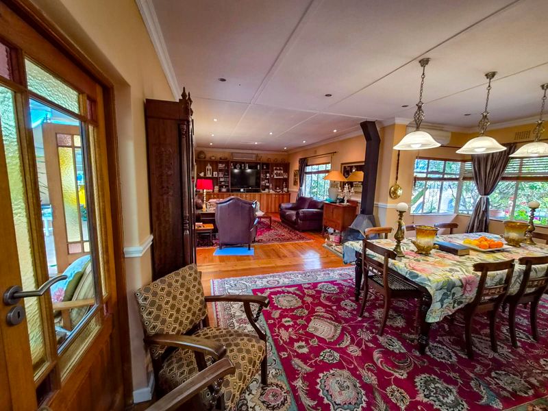 Spacious open-plan living and dining area featuring hardwood flooring, a freestanding fireplace, and built-in cabinetry, offering a warm and traditional aesthetic.