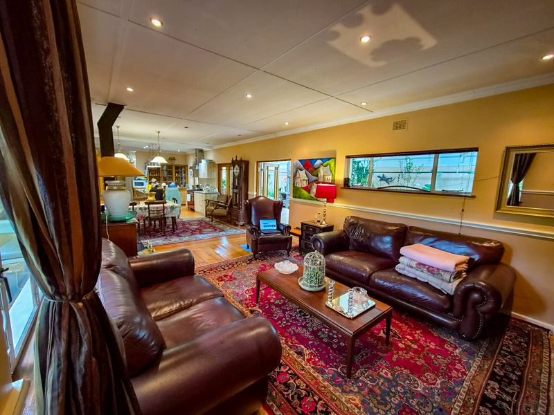 Spacious open-plan living and dining area featuring hardwood floors, recessed lighting, and a connected kitchen with built-in cabinetry and a fireplace.