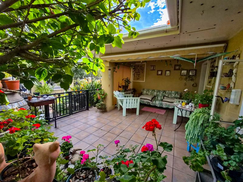 A covered outdoor patio area featuring tiled flooring and metal railings, providing a pleasant space for relaxation and outdoor living.