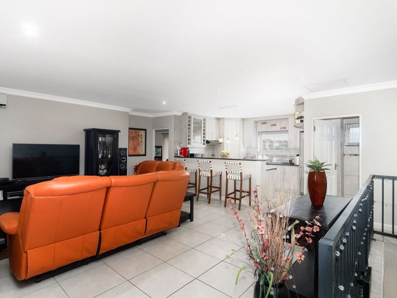 An open-plan living and kitchen area featuring tiled flooring, recessed lighting, and a functional breakfast bar layout.