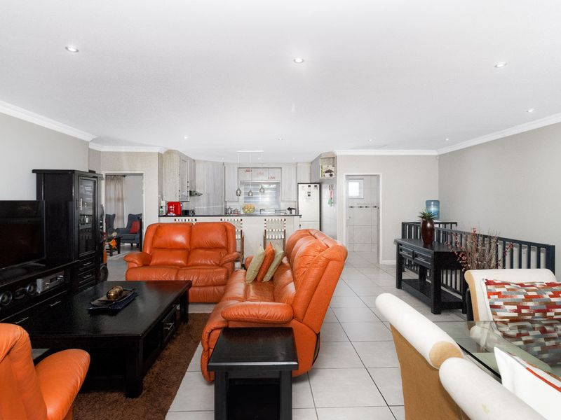 Spacious open-plan living and dining area featuring tiled floors, recessed lighting, and a functional kitchen with a central island.