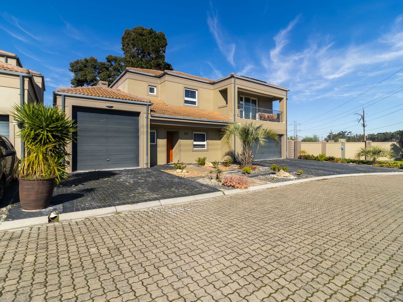 A modern double-story residential property featuring a paved driveway, double garage, and an upper-level balcony with a neutral exterior finish.