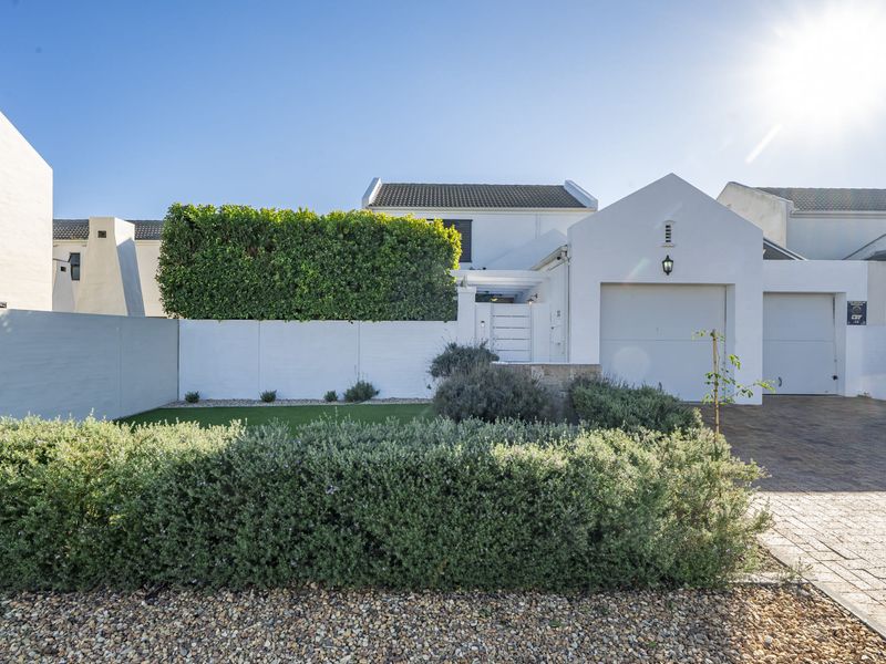 Front elevation of a well-maintained residence featuring a paved driveway, integrated garage, and neatly landscaped garden with established boundary walls.