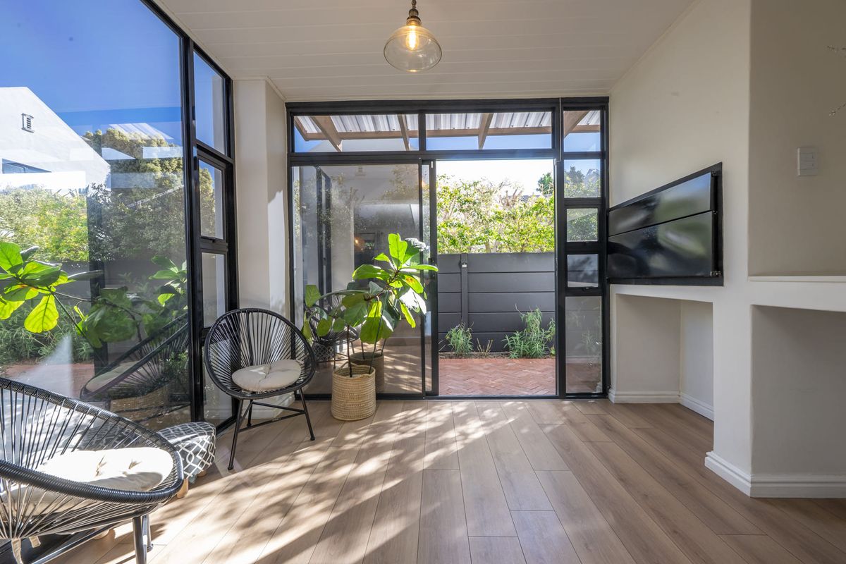 Bright living area featuring expansive floor-to-ceiling glass windows and sliding doors that provide seamless access to the outdoor patio area.
