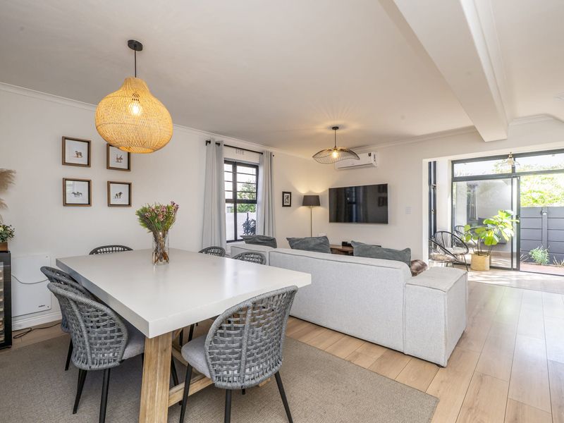 Bright open-plan living and dining area featuring laminate flooring, modern pendant lighting, and large sliding glass doors providing seamless access to the outdoor space.