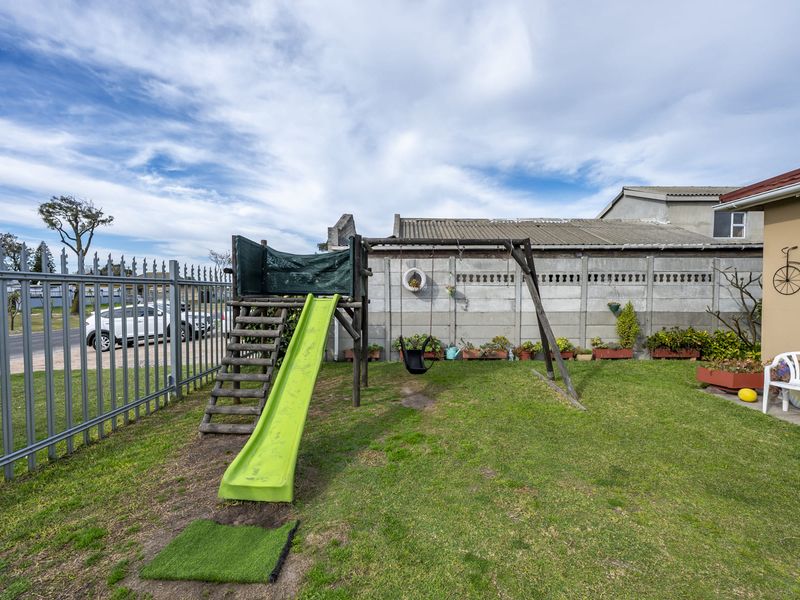 A private garden area featuring a lawn, precast concrete boundary wall, and metal perimeter fencing.