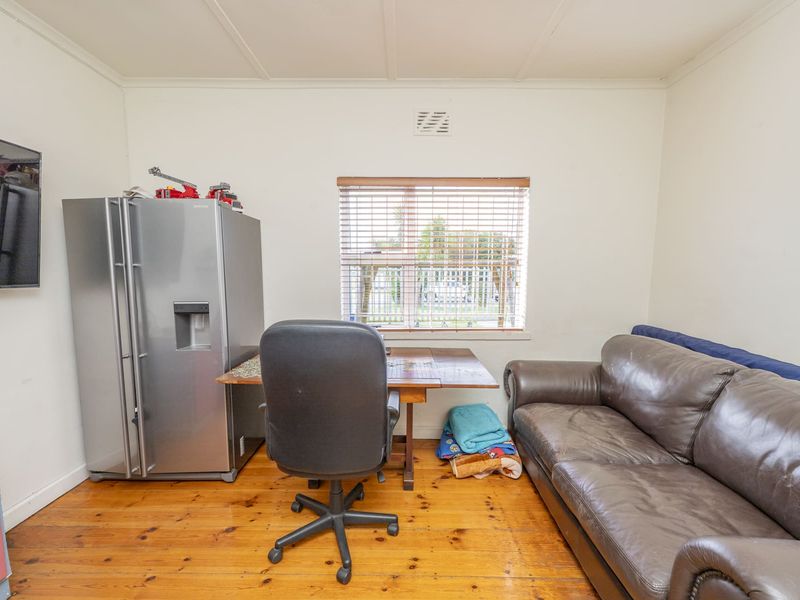 A functional office space featuring original timber flooring and a window with venetian blinds, offering a versatile area for work or study.