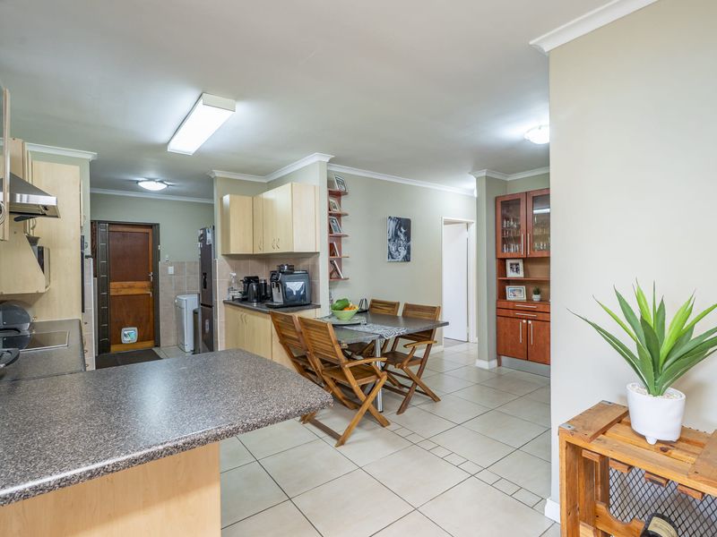 Open plan kitchen and dining area featuring laminate cabinetry, stone-look countertops, and neutral ceramic floor tiles throughout the living space.