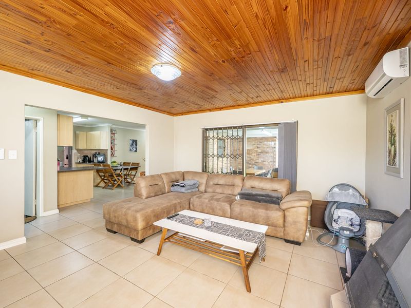 Open plan living area featuring tiled floors, a timber ceiling, built-in fireplace, and split system air conditioning, with direct access to the patio.