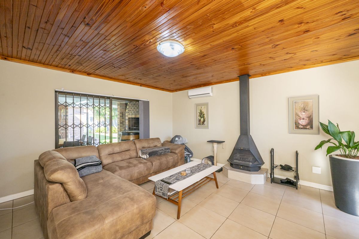 Comfortable living room featuring a wood-paneled ceiling, tiled flooring, a freestanding fireplace, and a split-system air conditioner, with access to an outdoor patio area.