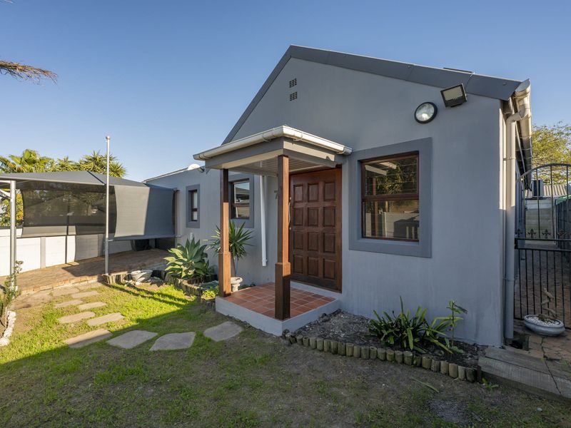Front elevation of a house featuring a timber entrance porch, tiled step, and a small garden area with a shade sail structure.