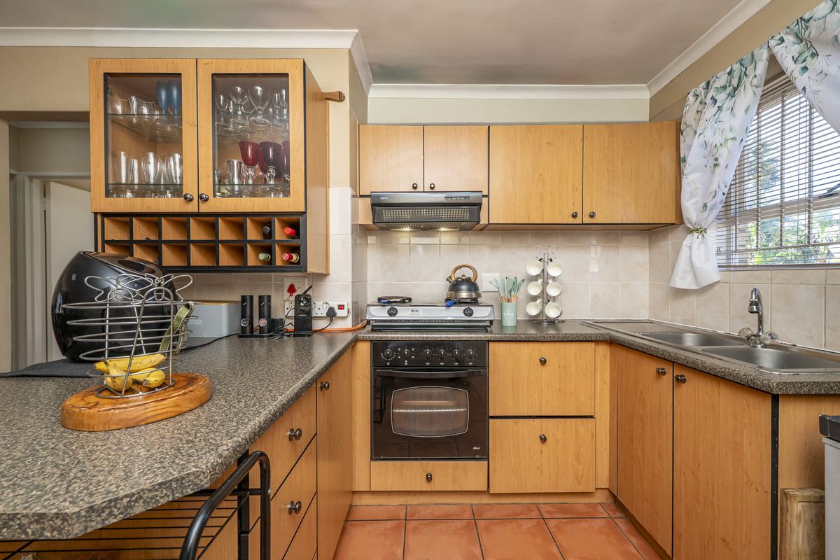 Functional kitchen featuring light wood cabinetry, granite-look countertops, built-in oven with gas hob, extractor fan, and a double bowl stainless steel sink.