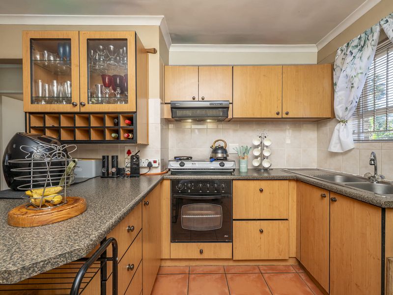 Functional kitchen featuring light wood cabinetry, granite-look countertops, built-in oven with gas hob, extractor fan, and a double bowl stainless steel sink.