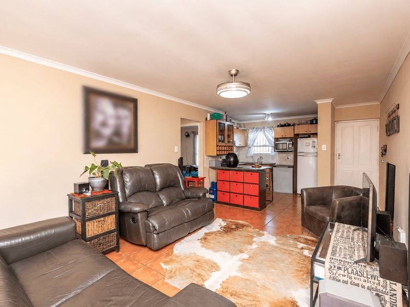 Open-plan living area featuring tiled flooring and a functional kitchen with built-in cabinetry and a central island.