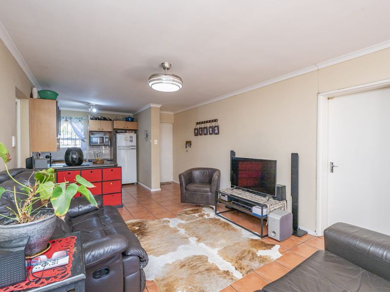 Open-plan living area featuring tiled flooring and a functional kitchen space with built-in cabinetry, creating a combined living and dining environment.
