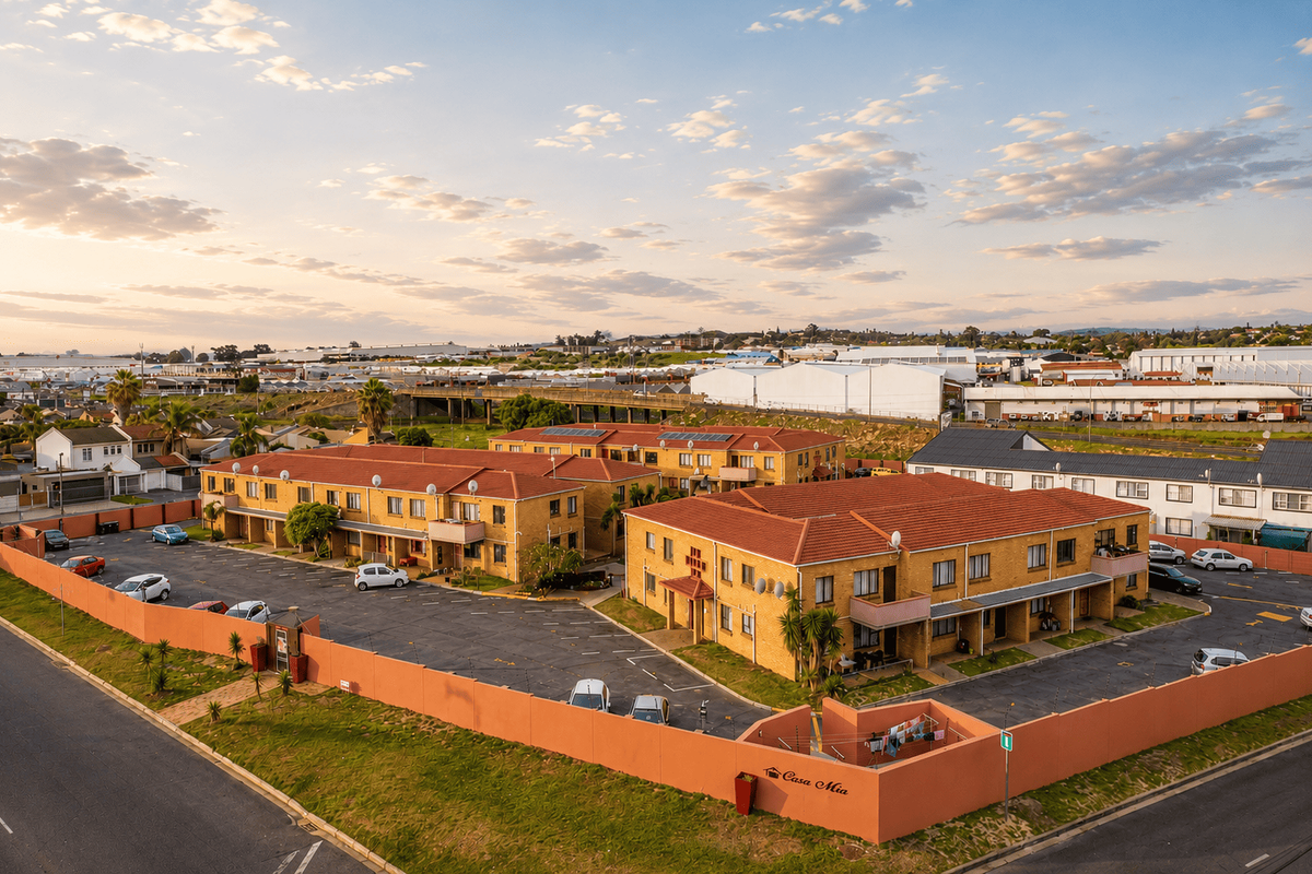 Aerial view of the Casa Mia apartment complex, featuring multiple residential blocks, a paved parking area, and perimeter security walls.