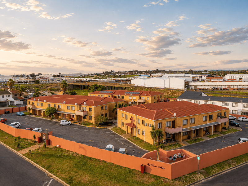 Aerial view of the Casa Mia apartment complex, featuring multiple residential blocks, a paved parking area, and perimeter security walls.