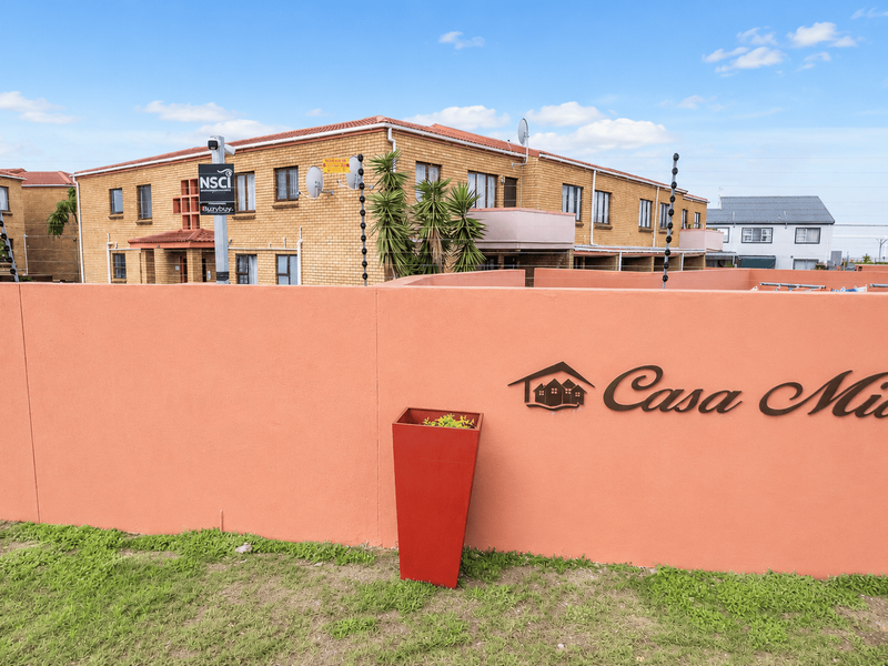 Front view of the Casa Mia apartment complex featuring a face brick facade, secure perimeter wall with electric fencing, and a tiled roof.