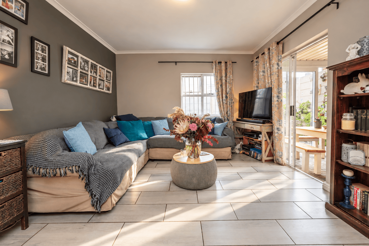 A well-lit living room featuring neutral tiled flooring, a feature wall, and large sliding glass doors providing direct access to an outdoor patio area.