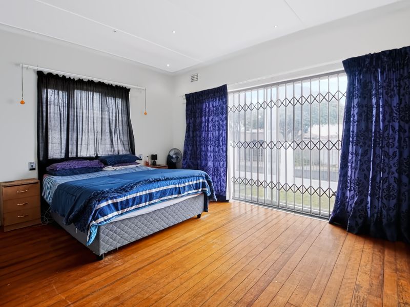 Spacious bedroom featuring original hardwood flooring, recessed lighting, and a large sliding glass door with a security gate leading to the exterior.