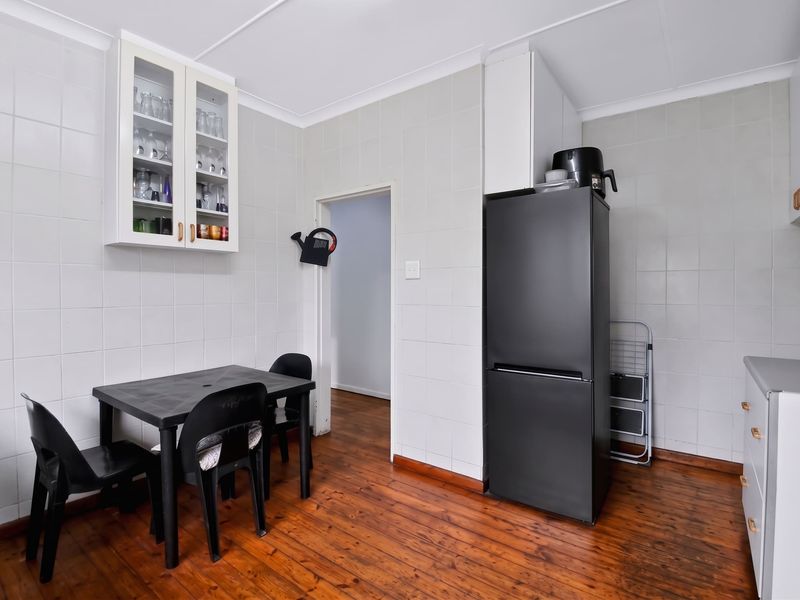 A functional kitchen area featuring tiled walls, timber flooring, and built-in cabinetry, providing a clean and practical space for daily use.