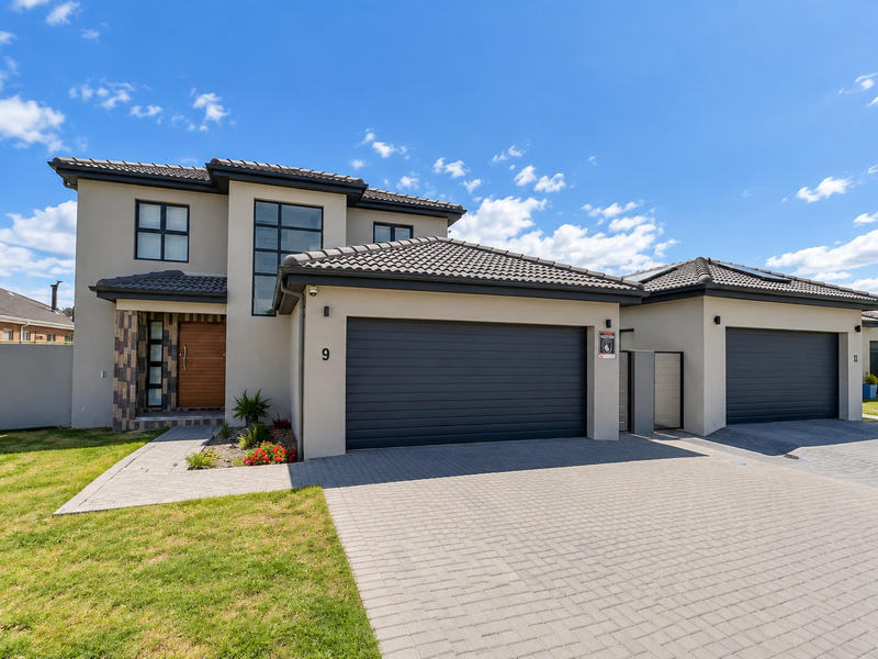Modern double-story townhouse featuring a paved driveway, double garage, and contemporary architectural facade with tiled roofing.