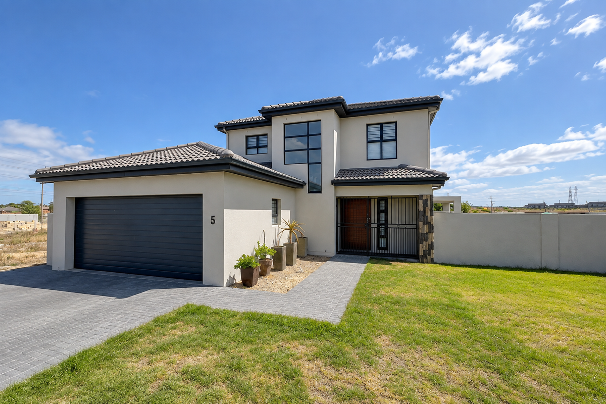 Modern double-story townhouse featuring a paved driveway, integrated double garage, secure entrance gate, and well-maintained exterior facade with contemporary architectural detailing.