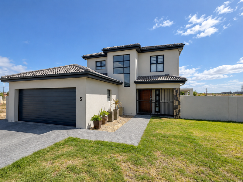 Modern double-story townhouse featuring a paved driveway, integrated double garage, secure entrance gate, and well-maintained exterior facade with contemporary architectural detailing.