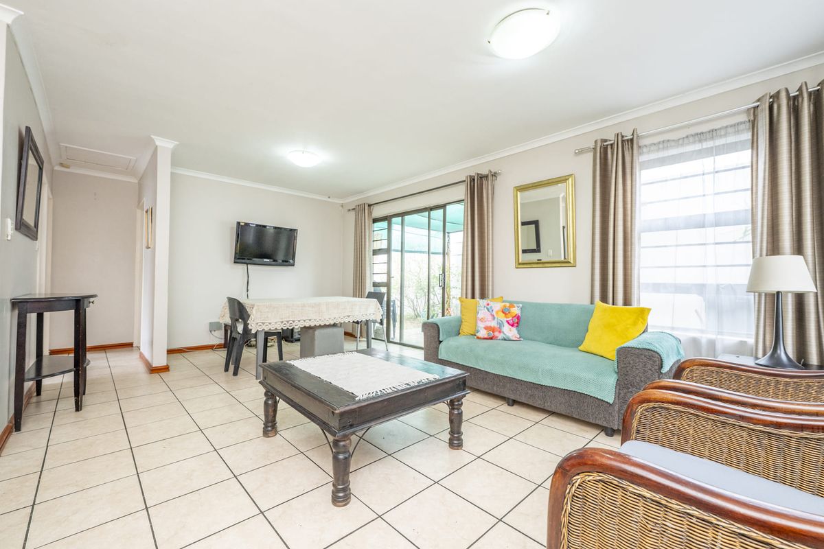 Spacious living area featuring neutral tiled flooring, coved cornicing, and a sliding glass door providing access to the outdoor space.