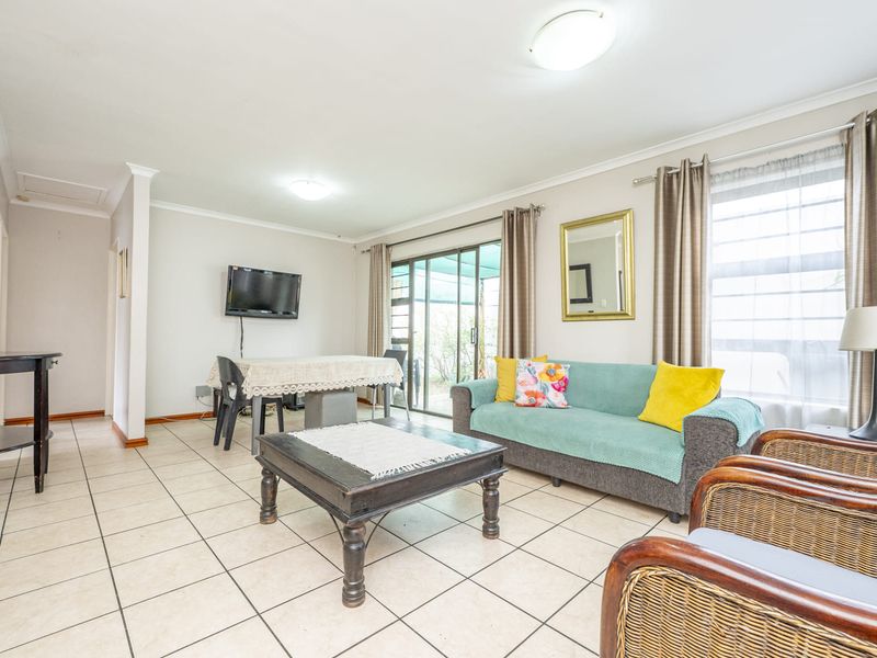 Spacious living area featuring neutral tiled flooring, coved cornicing, and a sliding glass door providing access to the outdoor space.