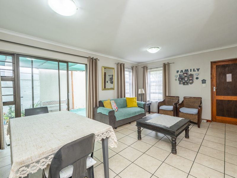 Open-plan living and dining area featuring tiled flooring, neutral walls, and large sliding glass doors providing access to the outdoor patio space.