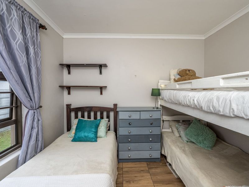 A functional bedroom featuring tiled flooring, built-in wall shelving, and a large window providing natural light.