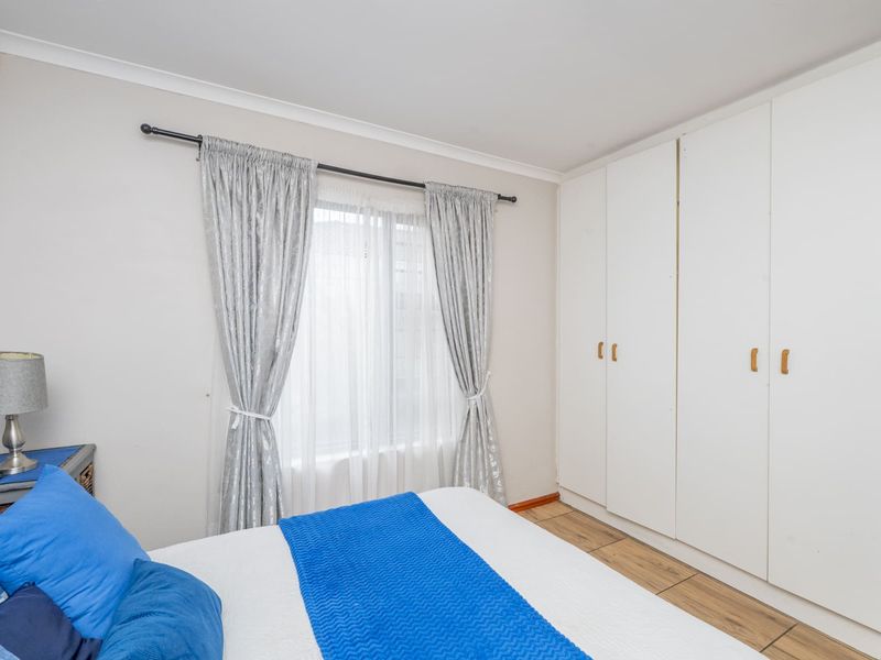 A functional bedroom featuring built-in cupboards, laminate flooring, and neutral wall finishes, providing a clean and practical living space.