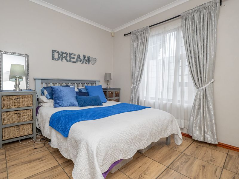 A well-lit bedroom featuring tiled flooring and neutral wall finishes, providing a comfortable and functional living space.