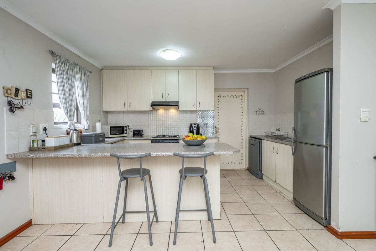 A functional kitchen featuring light-toned cabinetry, laminate countertops, tiled backsplash, and a breakfast bar, providing a practical layout for daily meal preparation.