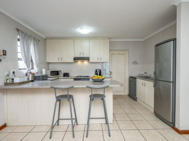 A functional kitchen featuring light-toned cabinetry, laminate countertops, tiled backsplash, and a breakfast bar, providing a practical layout for daily meal preparation.