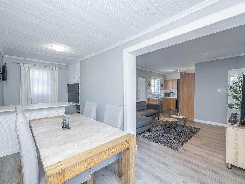 Open-plan living and dining area featuring laminate flooring, a built-in fireplace, and a connected kitchen with modern cabinetry.