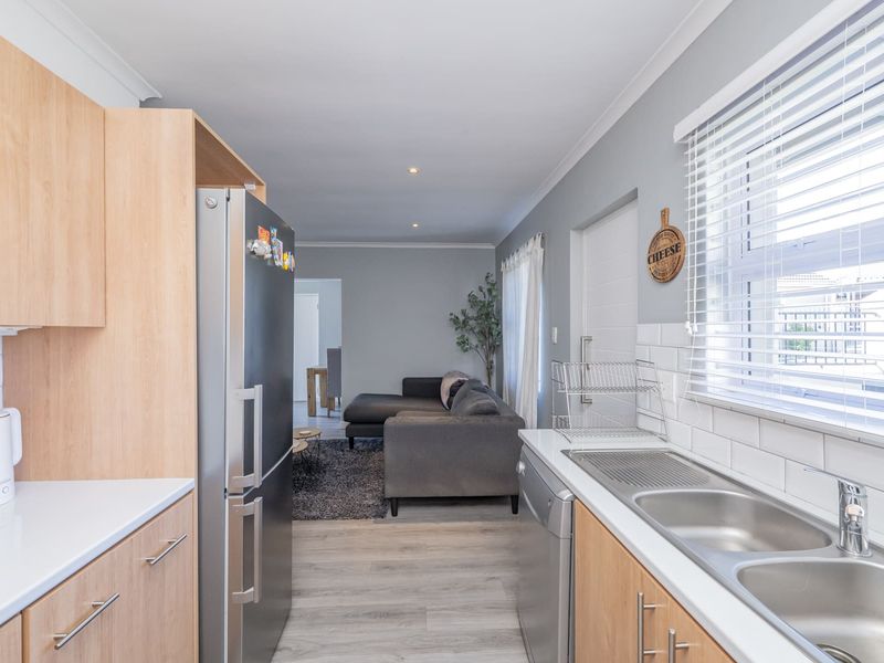 Open-plan kitchen featuring light-wood cabinetry, white subway tile backsplash, and quartz countertops, flowing seamlessly into the adjacent living area.